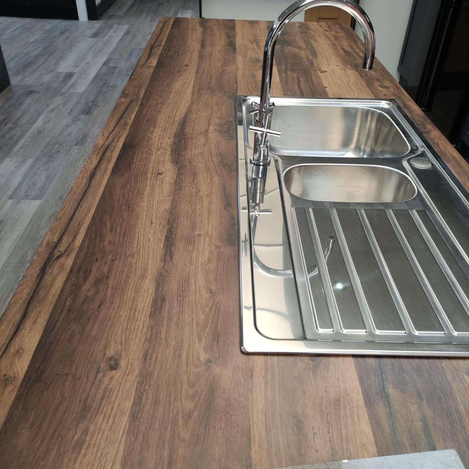A stainless steel sink inset into a wood-effect worktop