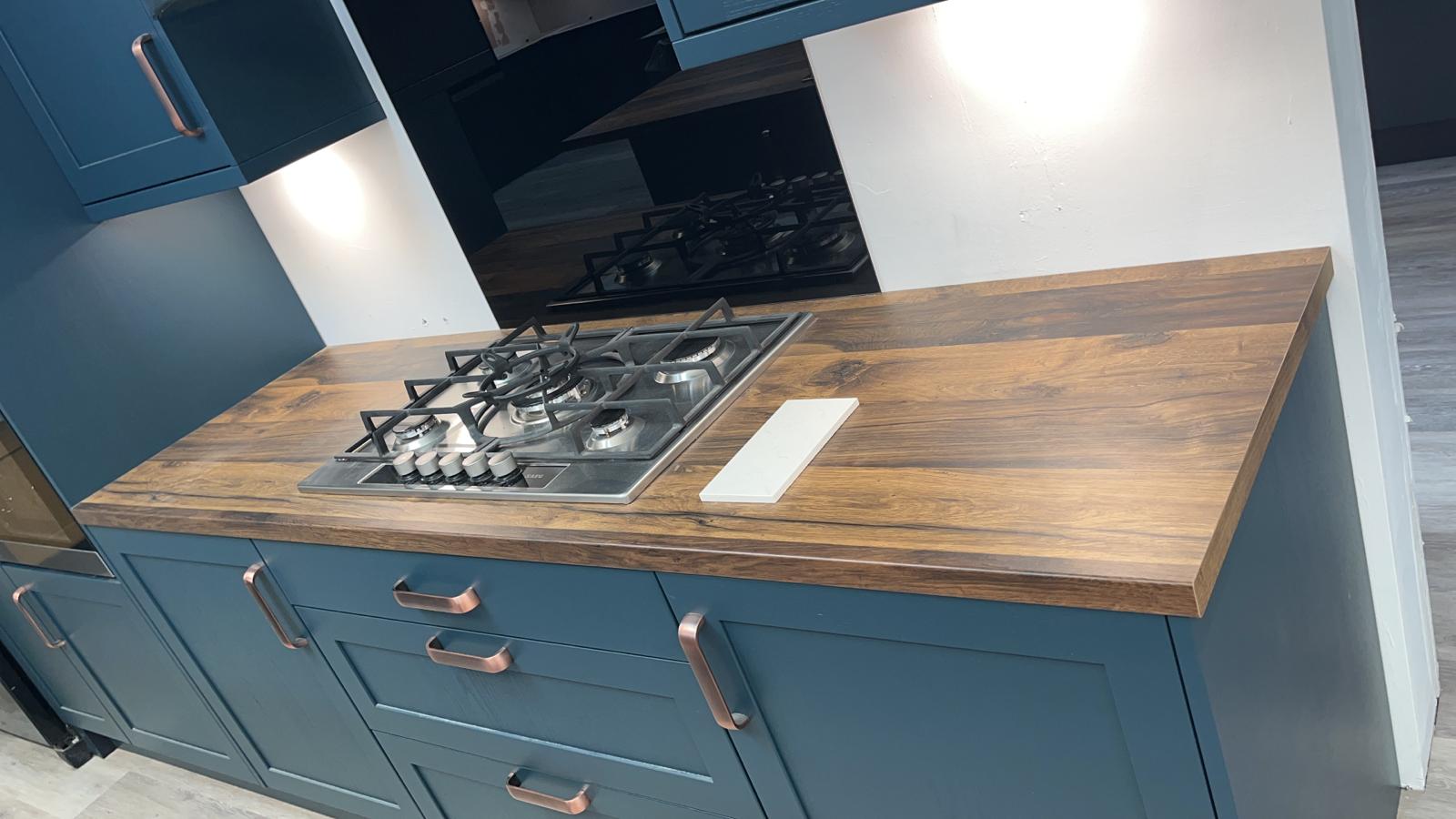 Navy kitchen units with a gas hob set into a wood-effect worktop