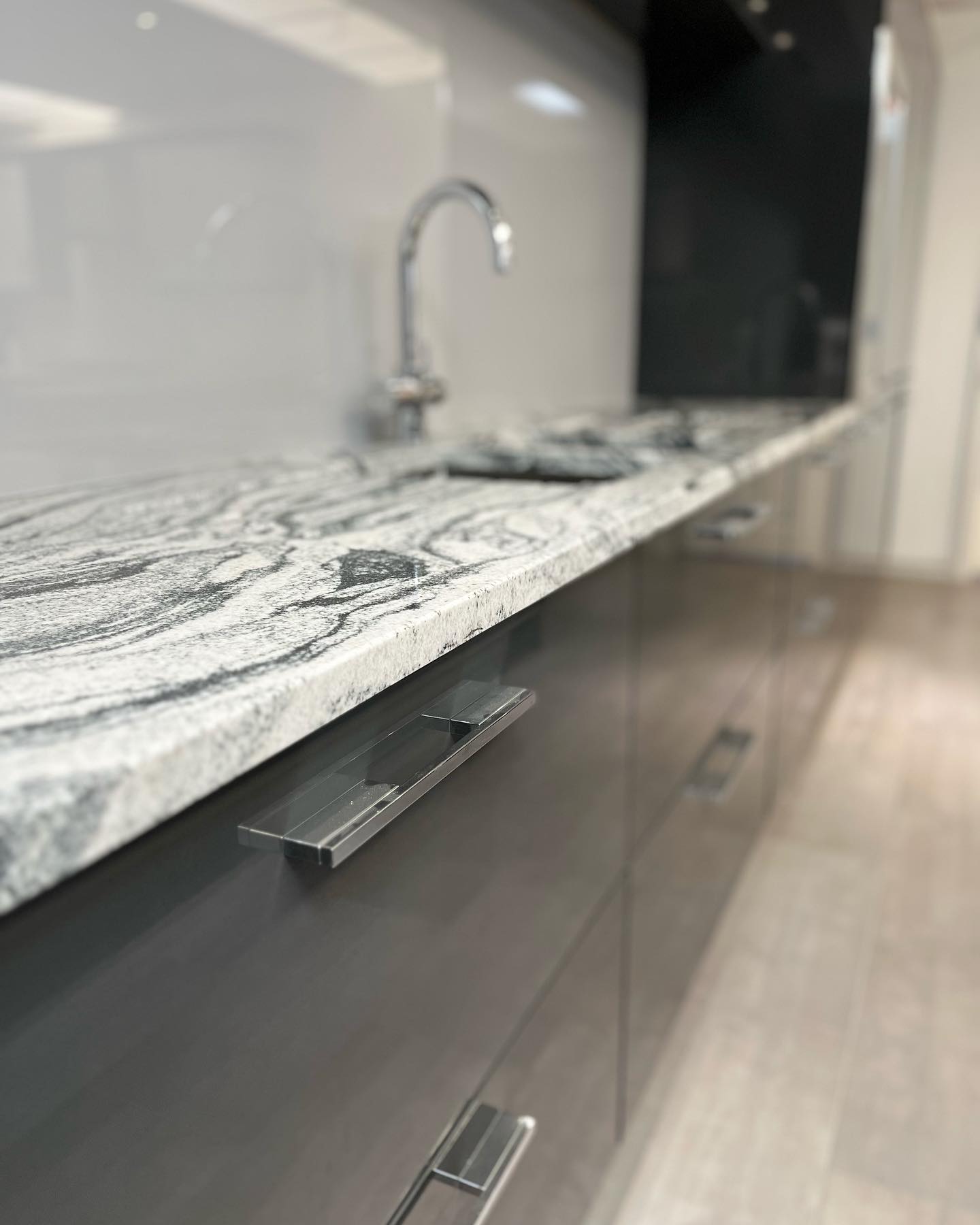 Grey gloss kitchen units with a veined worktop and a chrome tap